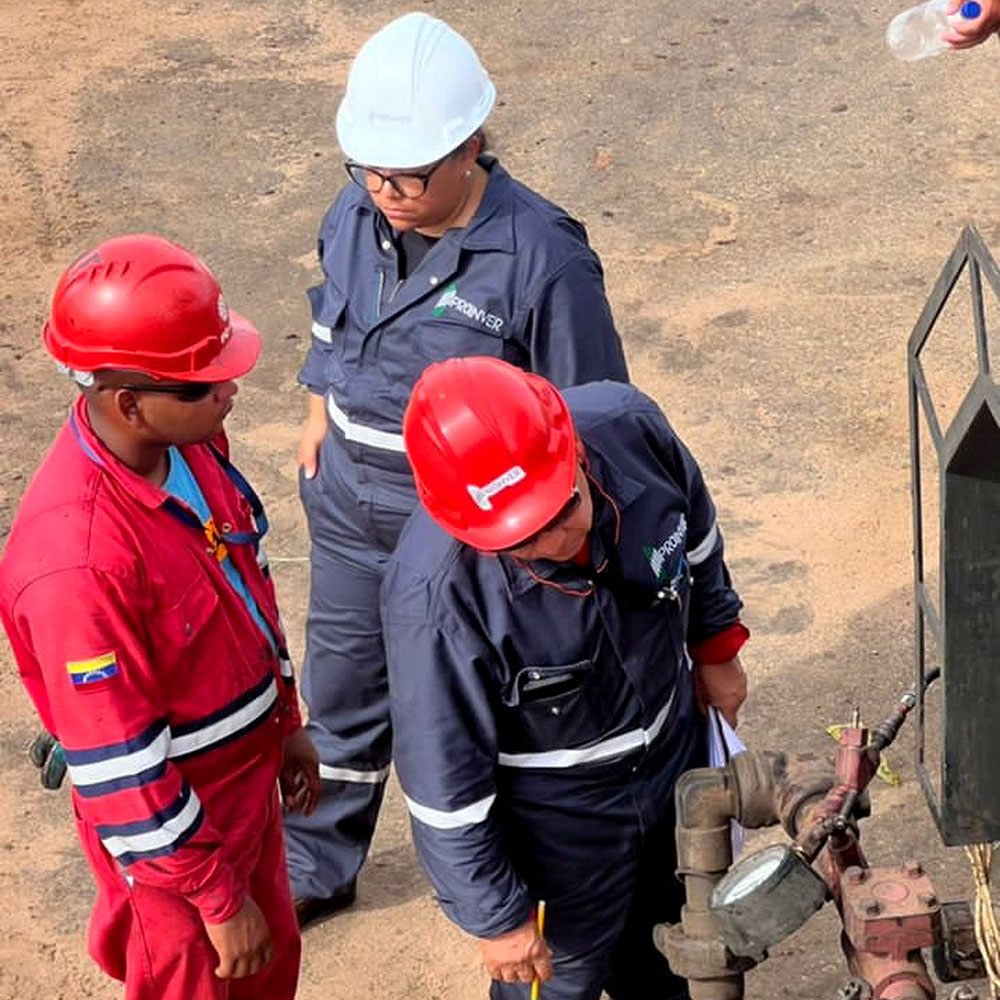 Personal con cascos examinando una conexión o equipo en campo.